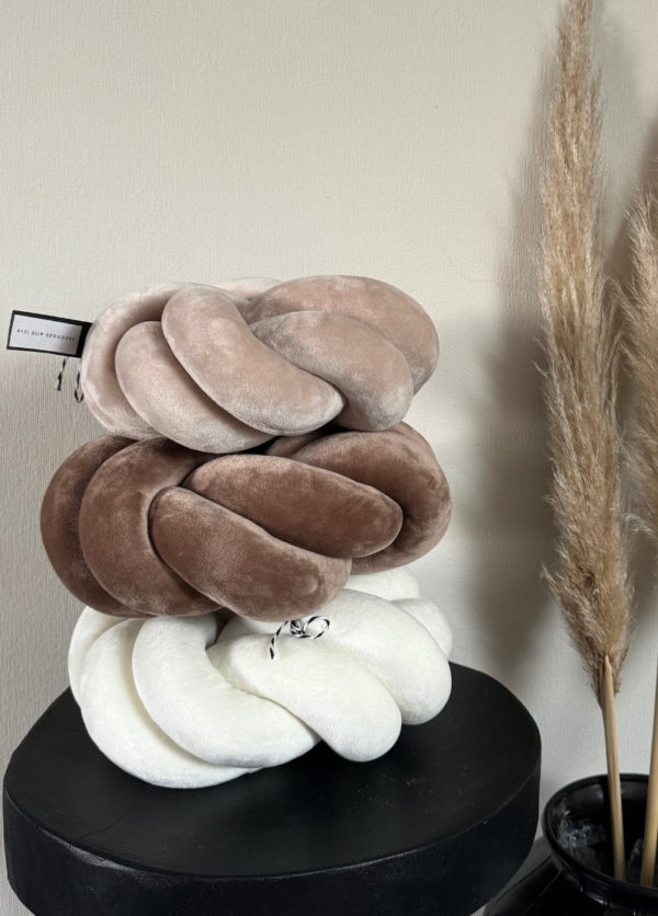 drei Swirl-Knotenkissen, die übereinander gestapelt sind. In den Farben hellbeige, dunkelbeige, cremeweiß