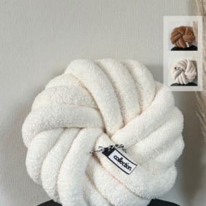 Handgefertigtes Swirl aus weichem Teddy in der Farbe cremeweiß, präsentiert auf einem schwarzen Tisch