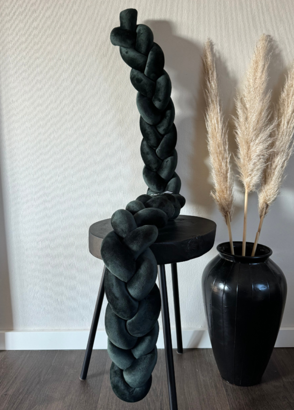 Bettschlange geflochten aus weichem Samt in dunkelgrün. Präsentiert auf einem schwarzen Tisch, daneben steht eine Vase mit Pampasgras.